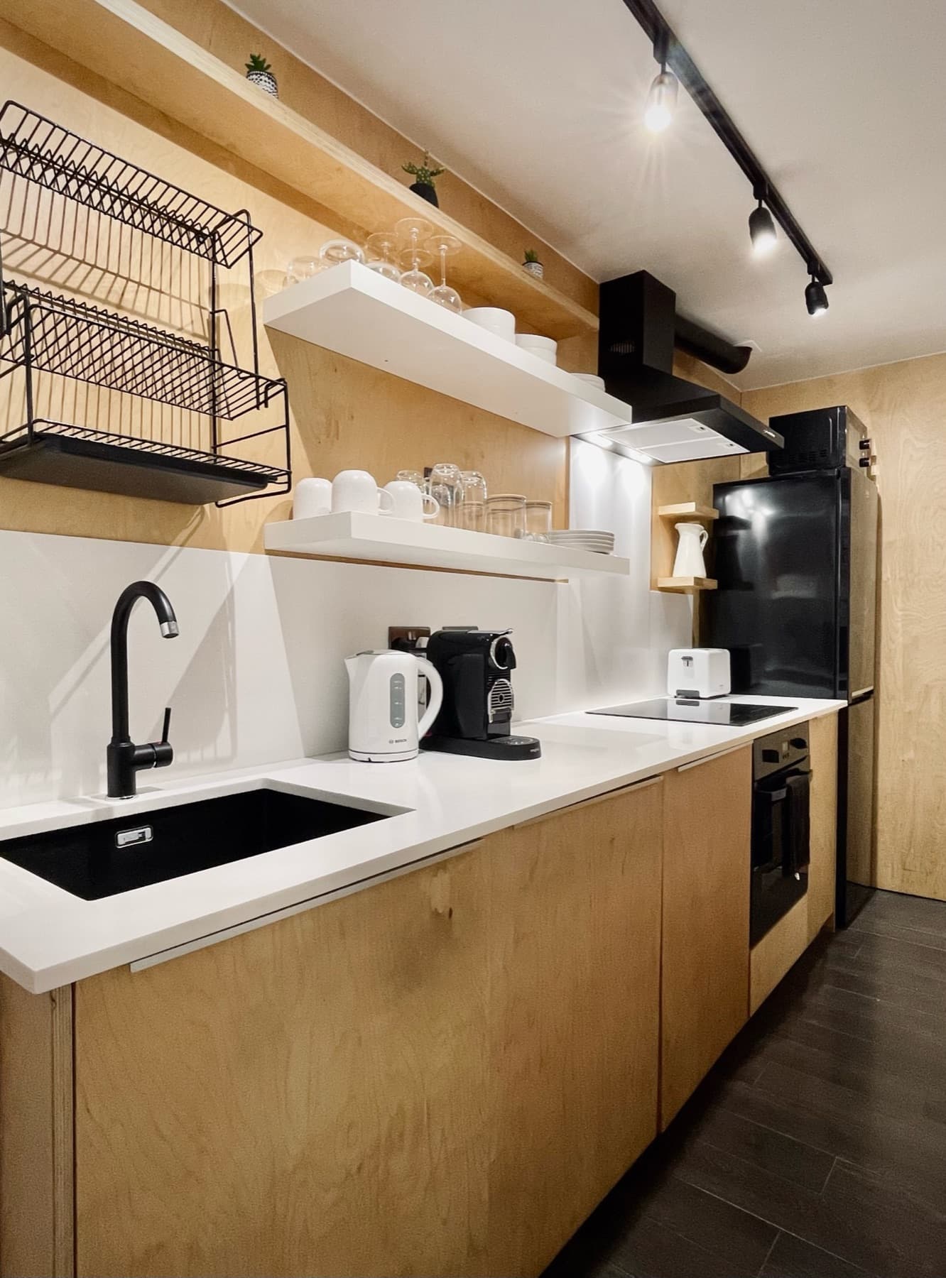 The kitchen — induction hob, Nespresso machine and warm plywood cabinetry